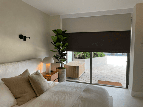 Double roller shades, brown and beige, installed in a bedroom