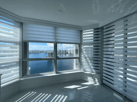 White zebra shades installed in three big windows facing the ocean