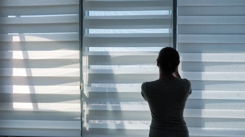 Woman lowering zebra shades on a sliding glass door
